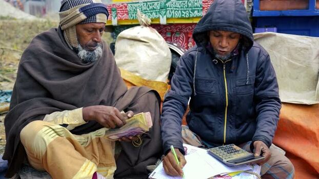 View of two men counting money and writing in a ledger Bangladesh. View of two men counting money and writing in a ledger Bangladesh.