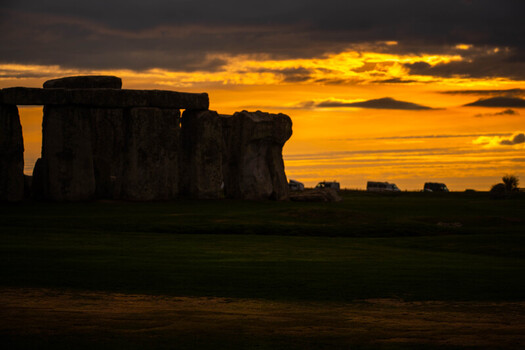 View of Stonehenge at sunset with golden light illuminating the horizon behind the ancient megalithic stones in Salisbury England United Kingdom.