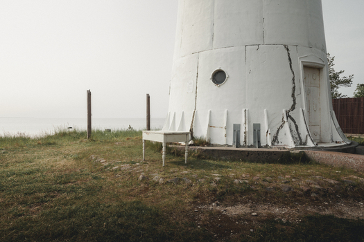 View of Saxby Lighthouse with a white wooden table on the grassy shore near the sea in Saxby Laane maakond Estonia.