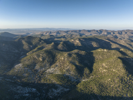 Aerial view of the Sierra de San Miguelito mountain range with rugged terrain dense vegetation and rolling hills under a clear sky in San Luis Potosi San Luis Potosi Mexico. Aerial view of the Sierra de San Miguelito mountain range with rugged terrain dense vegetation and rolling hills under a clear sky in San Luis Potosi San Luis Potosi Mexico.