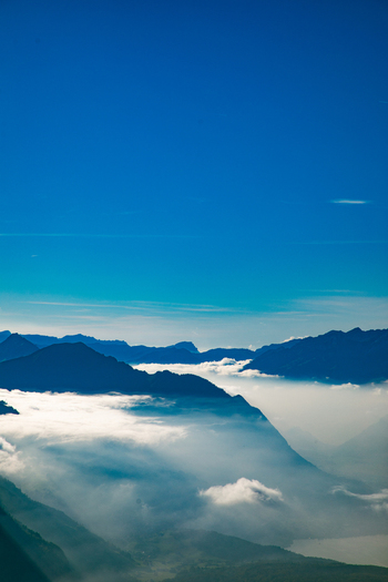 Aerial view of Swiss Alps with mountain peaks rising above a thick layer of clouds under a clear blue sky in Airolo Ticino Switzerland. Aerial view of Swiss Alps with mountain peaks rising above a thick layer of clouds under a clear blue sky in Airolo Ticino Switzerland.