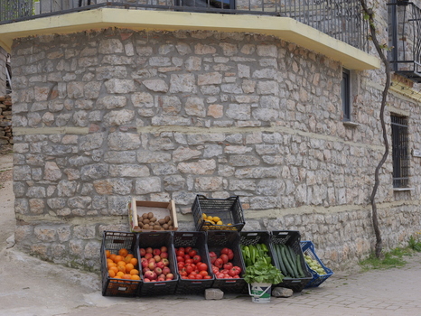 View of fresh produce displayed in crates against a rustic stone wall in the village of Lin Korce County Albania.