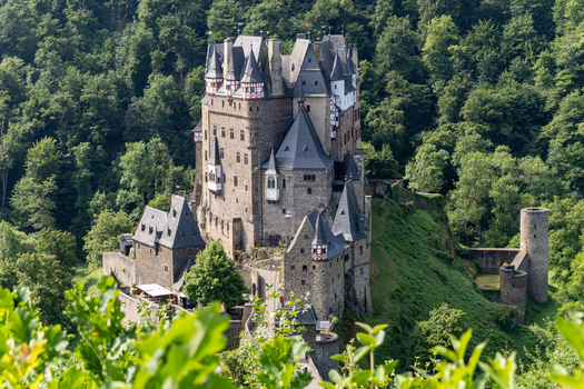 View of Eltz Castle with its medieval stone towers and timber framed architecture nestled in a lush green forest under bright daylight in Wierschem Rhineland Palatinate Germany.