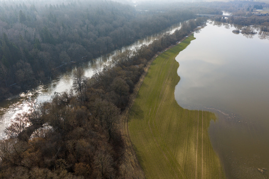 Aerial view of flooded green fields and a winding river bordered by a dense forest under a hazy sky in Kaniukai Kaunas County Lithuania. Aerial view of flooded green fields and a winding river bordered by a dense forest under a hazy sky in Kaniukai Kaunas County Lithuania.