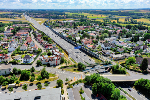 Aerial view of the A73 highway passing through residential neighborhoods with red roofed houses and lush green trees in Nurnberg Bayern Germany. Aerial view of the A73 highway passing through residential neighborhoods with red roofed houses and lush green trees in Nurnberg Bayern Germany.