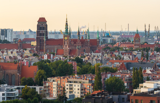 Aerial view of St. Mary s Church surrounded by historic red roofed buildings lush green trees and the urban skyline of Gdansk Pomeranian Voivodeship Poland. Aerial view of St. Mary s Church surrounded by historic red roofed buildings lush green trees and the urban skyline of Gdansk Pomeranian Voivodeship Poland.
