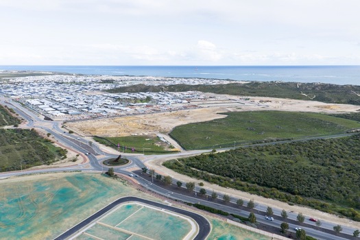 Aerial view of a residential development featuring a roundabout new road infrastructure and construction sites near the coast in Perth Western Australia Australia. Aerial view of a residential development featuring a roundabout new road infrastructure and construction sites near the coast in Perth Western Australia Australia.
