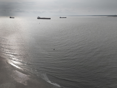 Aerial view of cargo ships anchored off the coast of Bonny Island with calm waters and a sandy shoreline in Bonny Town Rivers Nigeria. Aerial view of cargo ships anchored off the coast of Bonny Island with calm waters and a sandy shoreline in Bonny Town Rivers Nigeria.