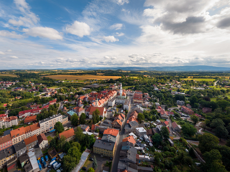 Aerial view of the historic town of Gryfow Slaski with red tiled rooftops church spire and green fields under a blue sky in Gryfow Slaski Lower Silesian Voivodeship Poland. Aerial view of the historic town of Gryfow Slaski with red tiled rooftops church spire and green fields under a blue sky in Gryfow Slaski Lower Silesian Voivodeship Poland.
