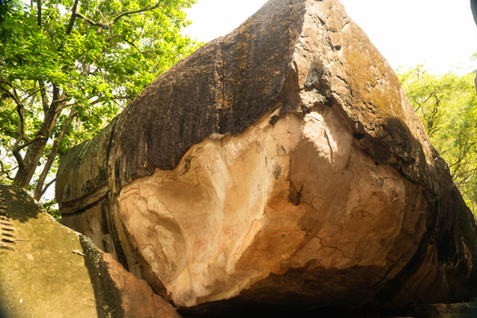 View of the ancient Cobra Hood Cave rock formation with weathered plaster and historical markings surrounded by lush green trees in Sigiriya Central Province Sri Lanka. View of the ancient Cobra Hood Cave rock formation with weathered plaster and historical markings surrounded by lush green trees in Sigiriya Central Province Sri Lanka.
