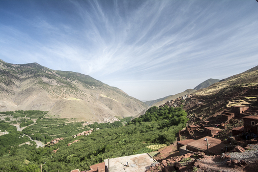 View of the traditional Berber village of Tizi Oussem in the High Atlas Mountains with terraced fields and lush greenery under a wispy blue sky Tizi Oussem Marrakech Safi Morocco. View of the traditional Berber village of Tizi Oussem in the High Atlas Mountains with terraced fields and lush greenery under a wispy blue sky Tizi Oussem Marrakech Safi Morocco.