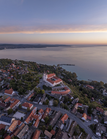 Aerial view of Tihany Abbey overlooking Lake Balaton at sunset with historic rooftops and lush greenery in Tihany Hungary. Aerial view of Tihany Abbey overlooking Lake Balaton at sunset with historic rooftops and lush greenery in Tihany Hungary.