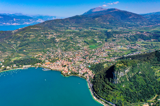 Aerial view of the town of Garda on the shores of Lake Garda with lush green hills mountains and turquoise water under a clear blue sky Garda Veneto Italy. Aerial view of the town of Garda on the shores of Lake Garda with lush green hills mountains and turquoise water under a clear blue sky Garda Veneto Italy.