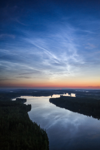 Aerial view of noctilucent clouds over the lake and forest landscape in Kangasniemi Etela Savo Finland.