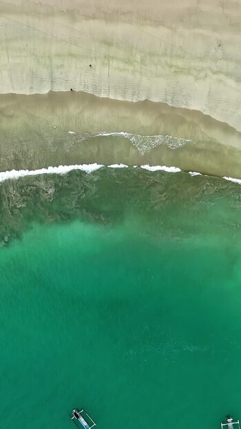 Aerial view of turquoise beach waters and boats in Bali Indonesia.