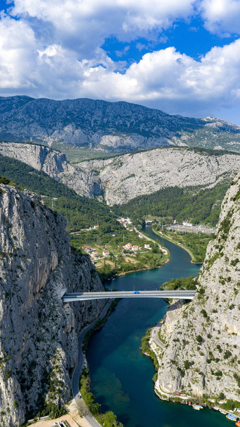 Aerial view of the Cetina River canyon and the modern bridge spanning between steep limestone cliffs in Omis Split Dalmatia County Croatia. Aerial view of the Cetina River canyon and the modern bridge spanning between steep limestone cliffs in Omis Split Dalmatia County Croatia.