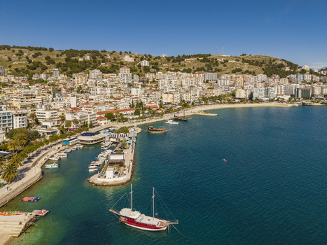 Aerial view of the coastal city of Saranda with its harbor docked boats and buildings rising up the hillside along the Ionian Sea in Saranda Vlore County Albania. Aerial view of the coastal city of Saranda with its harbor docked boats and buildings rising up the hillside along the Ionian Sea in Saranda Vlore County Albania.