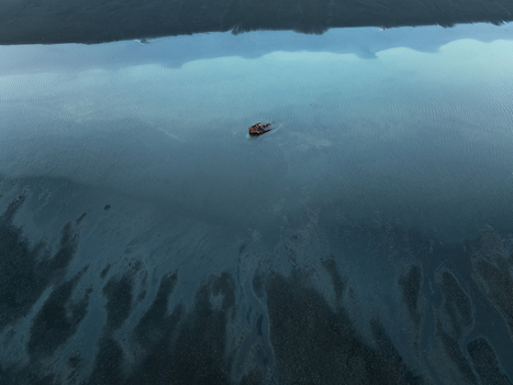 Aerial view of a rusted shipwreck stranded in the shallow tidal waters of a dark volcanic sand beach in Iceland. Aerial view of a rusted shipwreck stranded in the shallow tidal waters of a dark volcanic sand beach in Iceland.