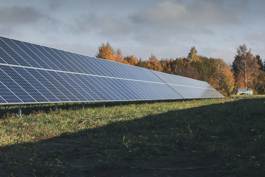 View of solar panels in a field with autumn trees in the background in Tartu County Estonia. View of solar panels in a field with autumn trees in the background in Tartu County Estonia.