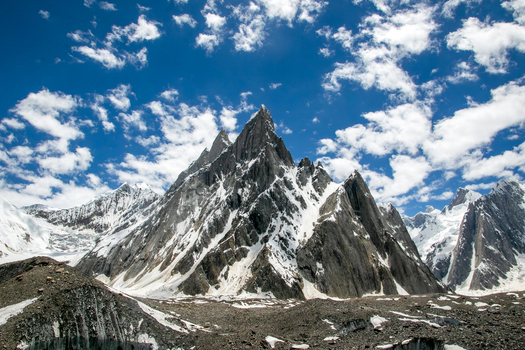View of the sharp summit of Mitre Peak with snow covered slopes under a blue sky with white clouds in Skardu Gilgit Pakistan.
