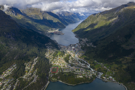 Aerial view of Odda town nestled between steep mountains at the end of Hardangerfjord with a river and football field Odda Vestland Norway. Aerial view of Odda town nestled between steep mountains at the end of Hardangerfjord with a river and football field Odda Vestland Norway.