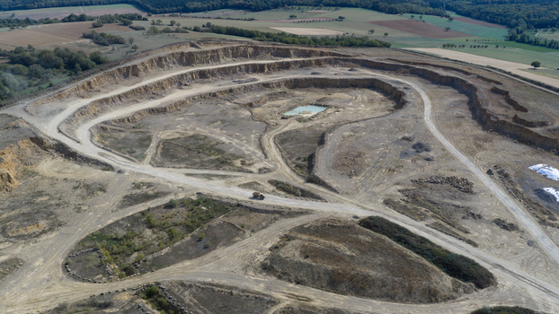 Aerial view of OPTERRA Wossingen GmbH quarry featuring terraced excavation levels dirt access roads and a small pond in the center Walzbachtal Baden Wurttemberg Germany. Aerial view of OPTERRA Wossingen GmbH quarry featuring terraced excavation levels dirt access roads and a small pond in the center Walzbachtal Baden Wurttemberg Germany.