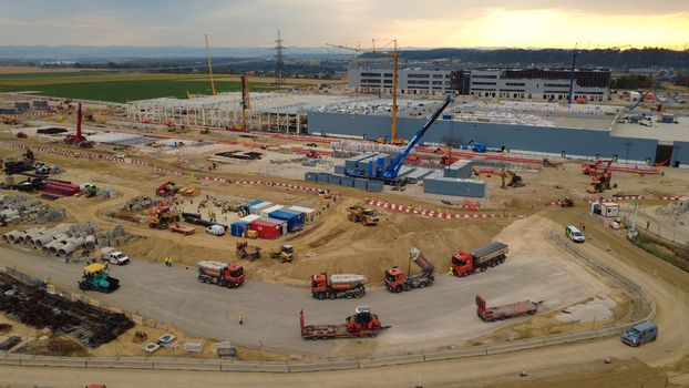 Aerial view of data center construction site with cranes heavy machinery and trucks operating during early morning hours in Kronstorf Upper Austria Austria.