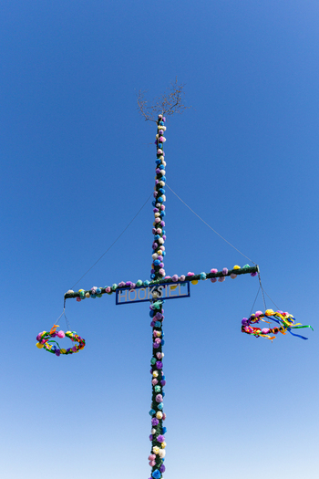 View of the traditional decorated maypole in Hooksiel with colorful floral ornaments and wreaths against a clear blue sky Wangerland Niedersachsen Germany. View of the traditional decorated maypole in Hooksiel with colorful floral ornaments and wreaths against a clear blue sky Wangerland Niedersachsen Germany.