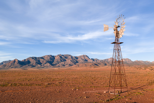 View of rustic metal windmill in an outback landscape with Heysen mountain range in background in Flinders Ranges South Australia Australia. View of rustic metal windmill in an outback landscape with Heysen mountain range in background in Flinders Ranges South Australia Australia.