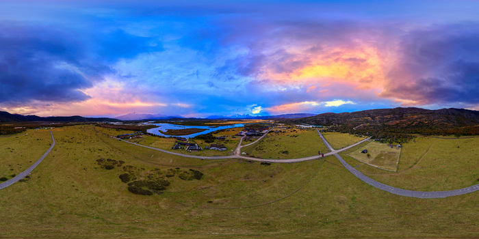 Aerial view of Rio Serrano Hotel and Spa near a winding river under a dramatic sunset sky with colorful clouds Torres de Paine Magallanes y la Antar Chile.