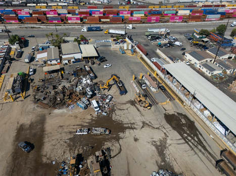 Aerial view of a scrap metal recycling facility with heavy machinery and piles of scrap metal located near a railway yard in Carson California United States.