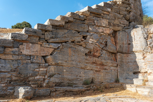 View of the Ancient Theatre of Thorikos showing weathered stone blocks ancient masonry and tiered seating under a clear blue sky in Thoricus Greece.