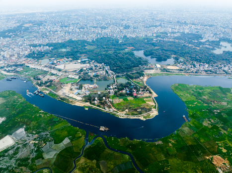 Aerial view of the winding river flowing through lush green fields and urban outskirts of Dhaka Dhaka Division Bangladesh. Aerial view of the winding river flowing through lush green fields and urban outskirts of Dhaka Dhaka Division Bangladesh.