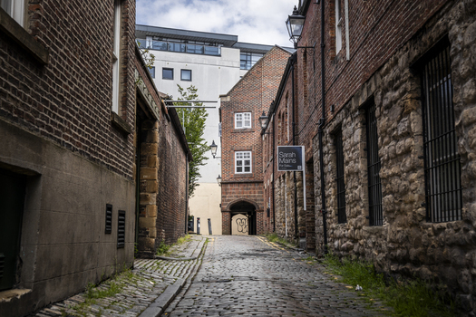 Newcastle upon Tyne England United Kingdom 13 July 2026 View of a narrow cobblestone street lined with historic brick and stone buildings and an archway. Newcastle upon Tyne England United Kingdom 13 July 2026 View of a narrow cobblestone street lined with historic brick and stone buildings and an archway.