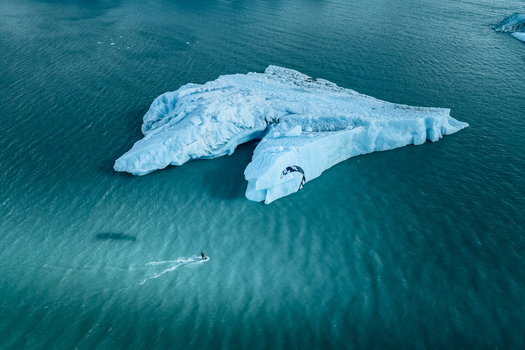 Aerial view of a kitesurfer gliding on turquoise water near a massive iceberg of the Perito Moreno glacier in Perito Moreno Santa Cruz Province Argentina.
