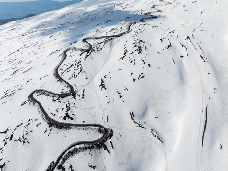 Aerial view of the winding SP92 road snaking through the snow covered volcanic landscape on the southern slope of Mount Etna Nicolosi Sicilia Italy. Aerial view of the winding SP92 road snaking through the snow covered volcanic landscape on the southern slope of Mount Etna Nicolosi Sicilia Italy.