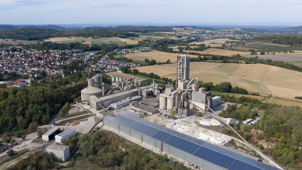 Aerial view of the OPTERRA Wossingen GmbH cement plant with large silos a tall concrete tower and industrial infrastructure surrounded by rural fields in Walzbachtal Baden Wurttemberg Germany. Aerial view of the OPTERRA Wossingen GmbH cement plant with large silos a tall concrete tower and industrial infrastructure surrounded by rural fields in Walzbachtal Baden Wurttemberg Germany.