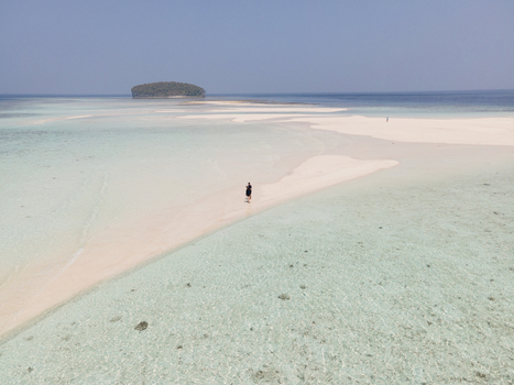 Aerial view of Pasir Timbul Mansuar sandbar surrounded by turquoise clear water and a distant island in Raja Ampat Papua Barat Indonesia. Aerial view of Pasir Timbul Mansuar sandbar surrounded by turquoise clear water and a distant island in Raja Ampat Papua Barat Indonesia.