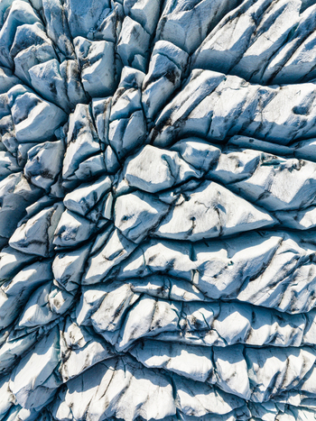 Aerial view of the intricate crevasses and textured ice formations of a glacier in Iceland. Aerial view of the intricate crevasses and textured ice formations of a glacier in Iceland.