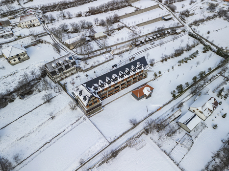 Aerial view of Camping Albania Boga Alpine Guest House surrounded by snow covered fields and rural landscape in winter in Boge Shkoder County Albania.