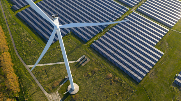 Aerial view of Solar park Delfzijl with a large wind turbine and rows of photovoltaic panels under bright sunlight in Farmsum Groningen Netherlands. Aerial view of Solar park Delfzijl with a large wind turbine and rows of photovoltaic panels under bright sunlight in Farmsum Groningen Netherlands.
