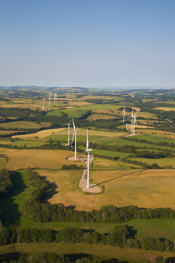 Aerial view of wind turbines standing tall against the patchwork of golden fields and dark green forests a testament to sustainable energy Salles Curan Occitanie France. Aerial view of wind turbines standing tall against the patchwork of golden fields and dark green forests a testament to sustainable energy Salles Curan Occitanie France.