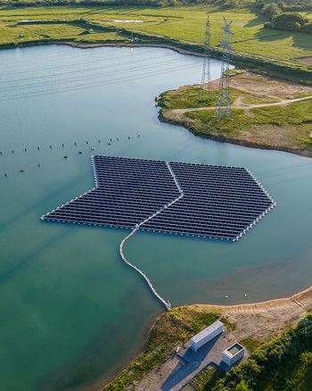 Aerial view of floating solar panels on a lake with green fields and power lines in Bensheim Hessen Germany. Aerial view of floating solar panels on a lake with green fields and power lines in Bensheim Hessen Germany.