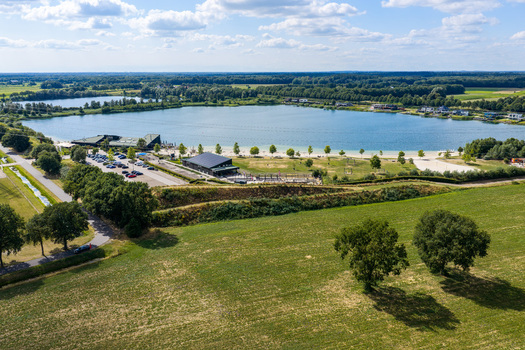 Aerial view of Strand Nijstad featuring a recreational lake sandy beach parking facilities and surrounding green fields in Hoogeveen Drenthe Netherlands.