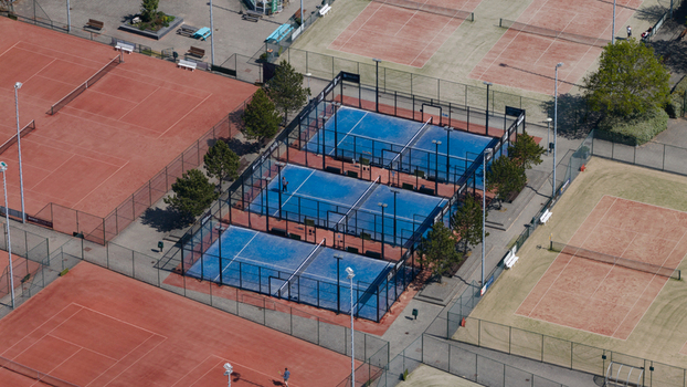 Aerial view of padel courts with blue surfaces surrounded by red clay tennis courts in a sports complex in Heiloo North Holland Netherlands.