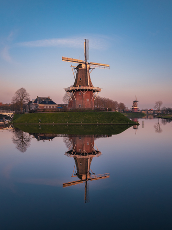 Aerial view of the historic De Hoop windmill and its perfect reflection on the calm canal water during a soft sunset Dokkum Friesland Netherlands. Aerial view of the historic De Hoop windmill and its perfect reflection on the calm canal water during a soft sunset Dokkum Friesland Netherlands.