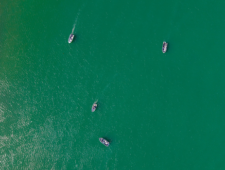 Aerial view of salmon fishing boats navigating the green waters in Gold Beach Oregon United States.