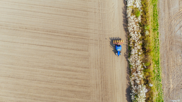 Aerial view of a vibrant blue tractor contrasting against the freshly tilled earth and the verdant strip of vegetation Sremska Mitrovica Vojvodina Serbia. Aerial view of a vibrant blue tractor contrasting against the freshly tilled earth and the verdant strip of vegetation Sremska Mitrovica Vojvodina Serbia.
