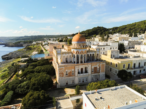 Aerial view of Villa Sticchi with its distinctive orange dome surrounded by historic architecture lush trees and the rocky coastline of Santa Cesarea Terme Apulia Italy.