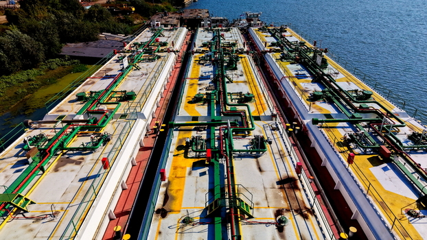 Aerial view of industrial barges with complex green and red piping systems and yellow deck markings docked on the Danube river in Smederevo Podunavlje District Serbia.